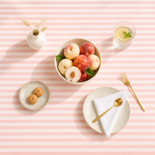 Nappe rayée pêche et blanc imperméable en coton peigné sur une table élégante avec pêches fraîches et citronnade